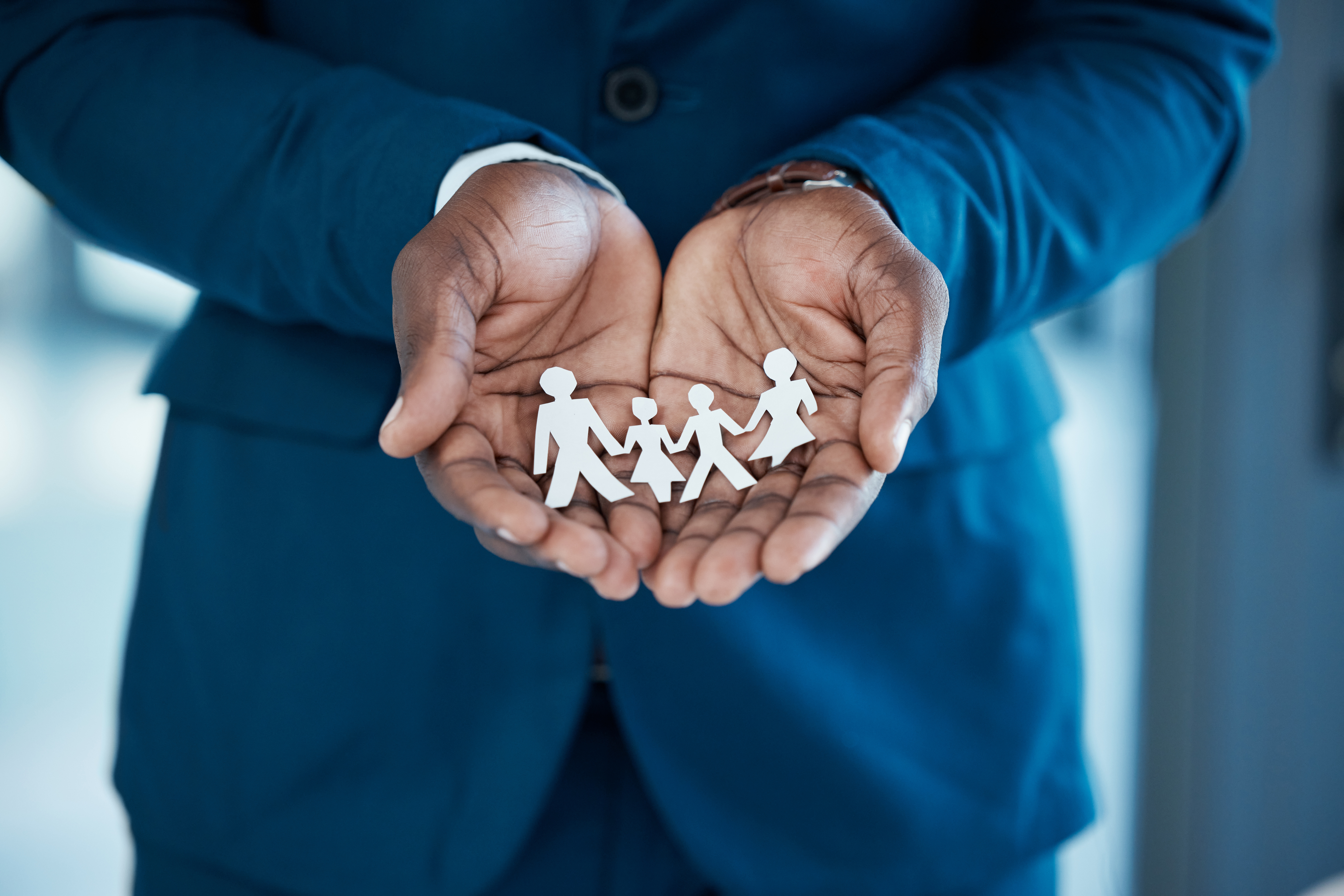 Business professional holding paper cutout family