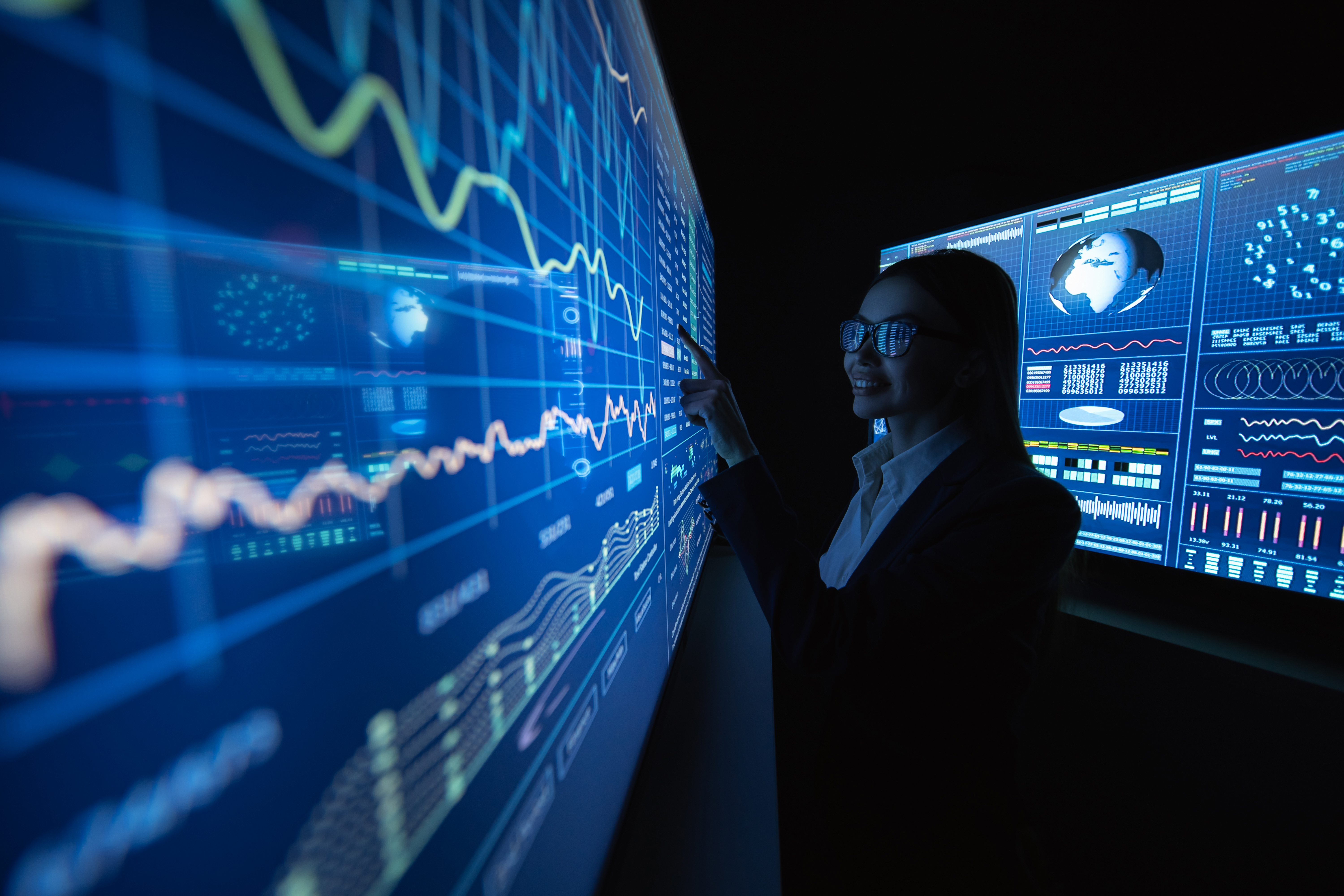 Woman analyzing data on digital screens